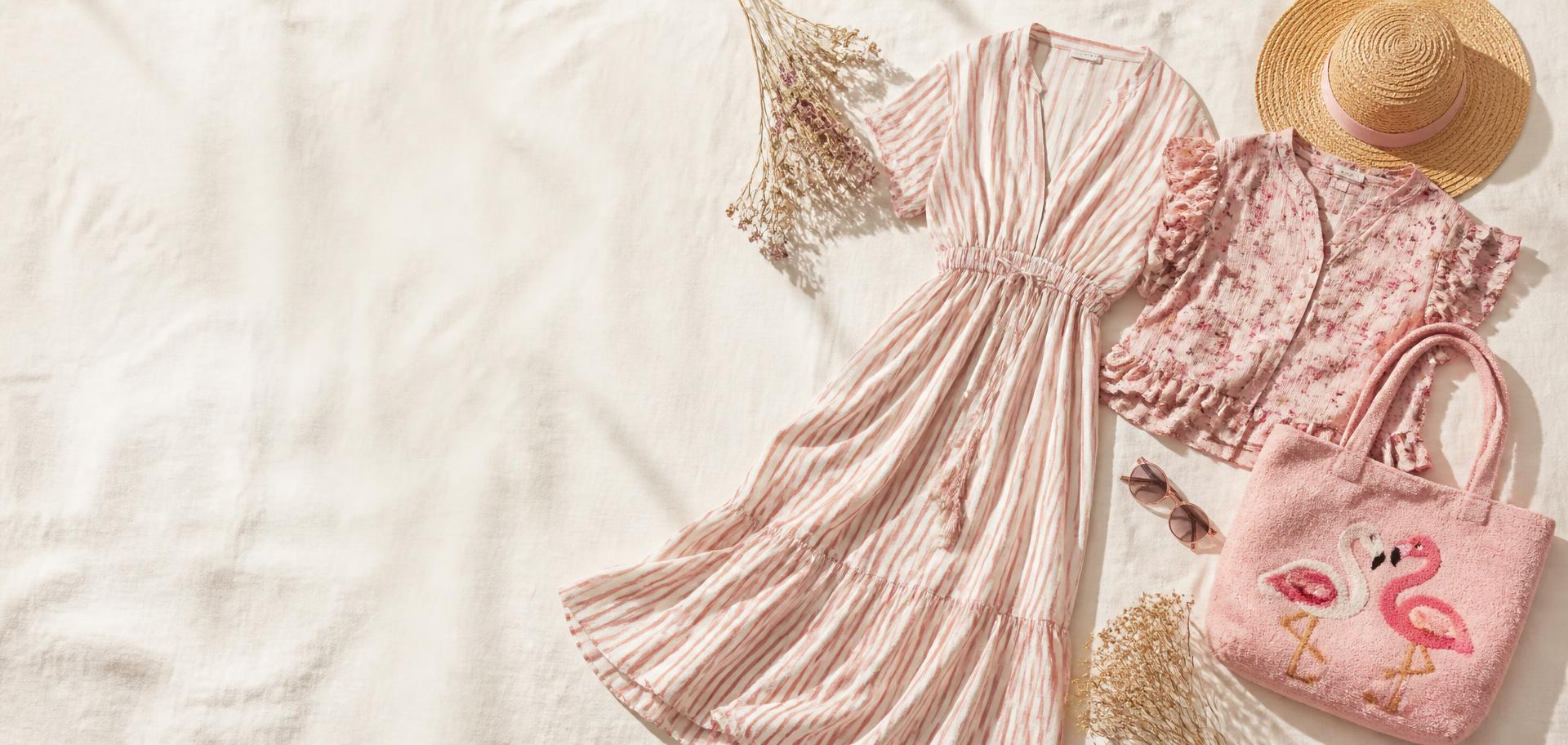Summer clearance flat lay with a striped maxi dress, floral blouse, straw hat and flamingo tote